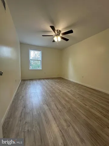 an empty room with wooden floor chandelier fan and windows