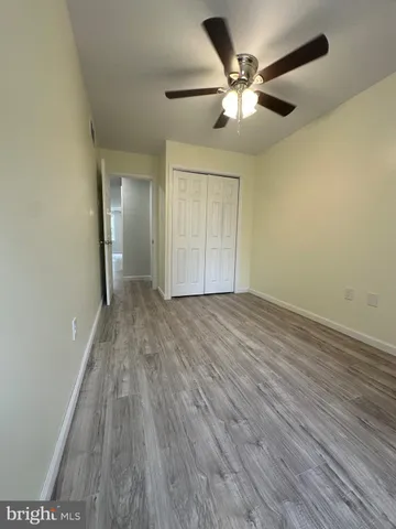 an empty room with wooden floor and a ceiling fan