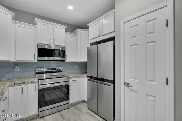 a kitchen with granite countertop a sink stainless steel appliances and white cabinets