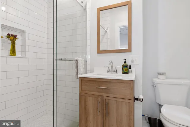 a bathroom with a granite countertop sink toilet and mirror