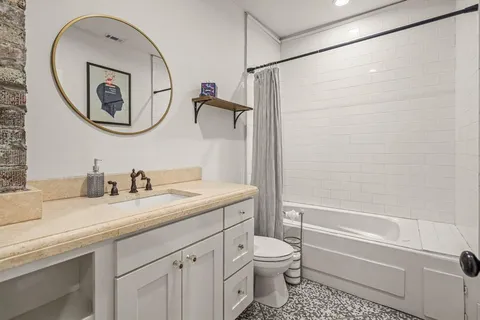 a bathroom with a granite countertop sink a toilet and a mirror