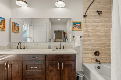 a bathroom with a double vanity sink a mirror and a bathtub