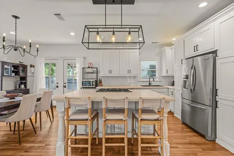 a kitchen with cabinets a center island stainless steel appliances and wooden floor