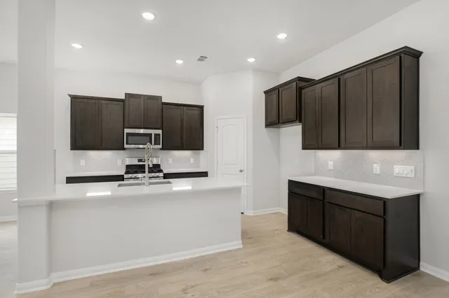 a kitchen with stainless steel appliances a sink a stove a microwave a counter top and cabinets