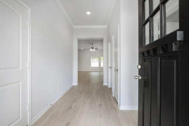 a view of a hallway with wooden floor and a bathroom