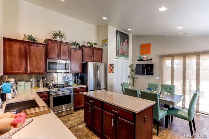 4068 Desert Ridge Circle Castle Rock, CO 80108 - Photo 8 of 25 a kitchen with stainless steel appliances granite countertop a table chairs and a refrigerator