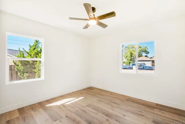 an empty room with windows and fan