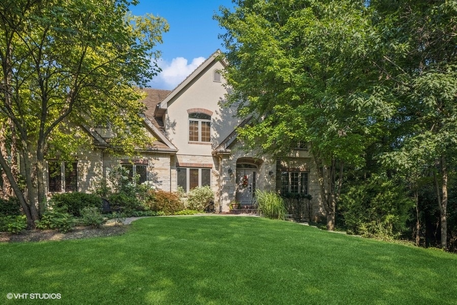 a front view of a house with a garden and trees