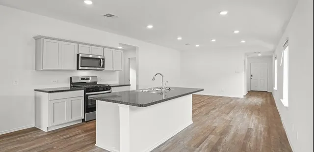 a kitchen with sink a microwave and cabinets
