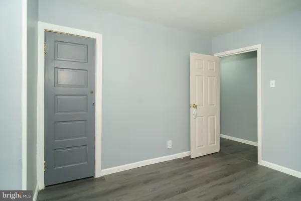 a view of an empty room with closet and wooden floor