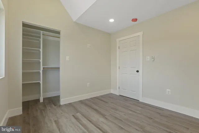 a view of an empty room with wooden floor and closet