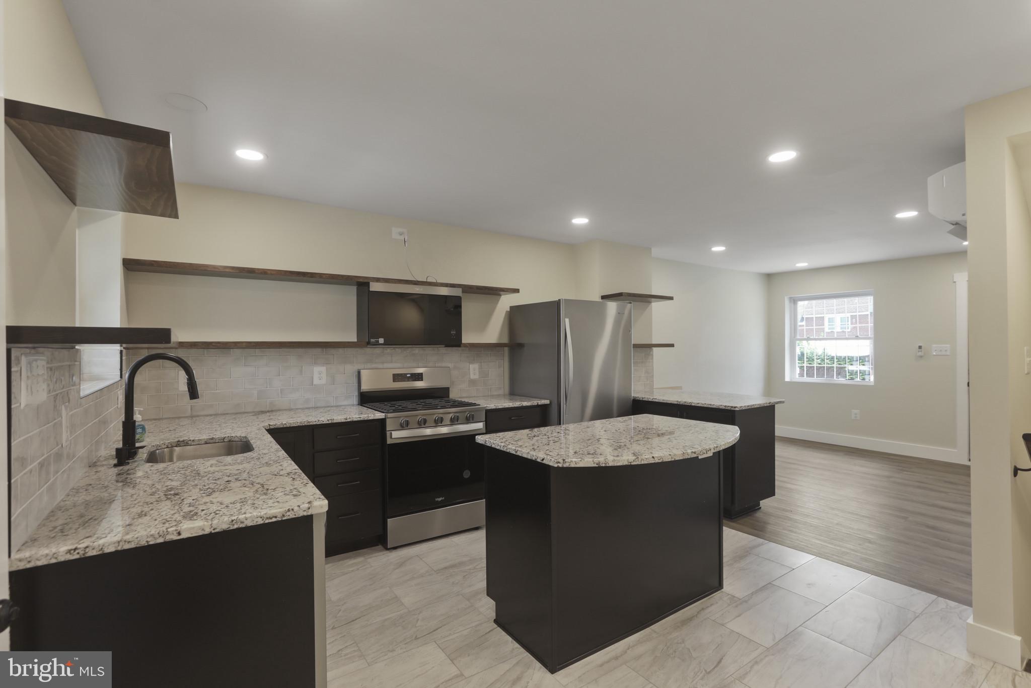 3828 10th Street Baltimore, MD 21225 - Photo 5 of 27 a kitchen with stainless steel appliances granite countertop a sink counter space cabinets and a window