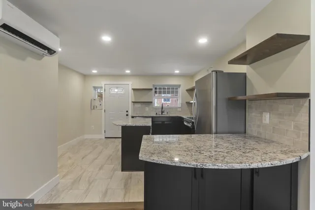 a kitchen with kitchen island a sink granite counter tops and a refrigerator