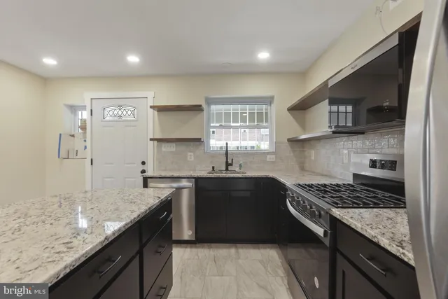 a kitchen with stainless steel appliances granite countertop a sink stove and cabinets
