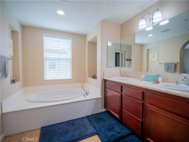 a bathroom with a tub a sink double vanity and a mirror