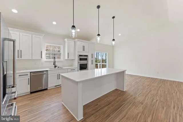 a large kitchen with cabinets wooden floor and stainless steel appliances