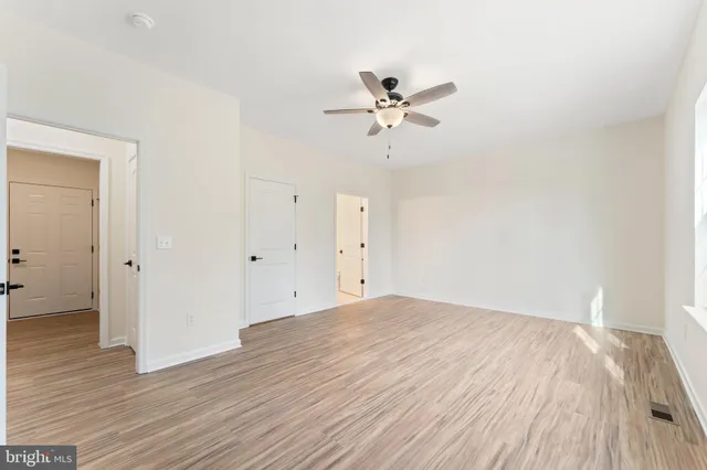 a view of an empty room with a window and wooden floor