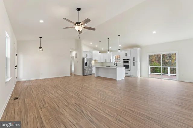 a view of empty room with wooden floor and fan