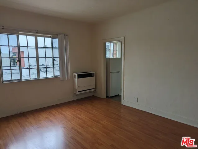 a view of an empty room with a window and wooden floor