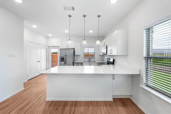 a large kitchen with stainless steel appliances a large counter top a refrigerator a sink and a stove