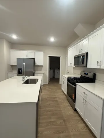 a large kitchen with stainless steel appliances kitchen island granite countertop a sink a stove top oven a counter space and cabinets