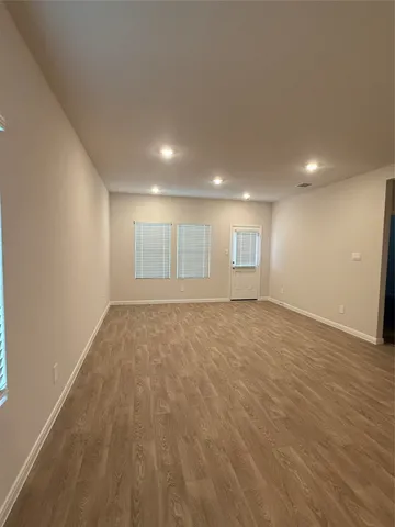 a view of an empty room with wooden floor and window