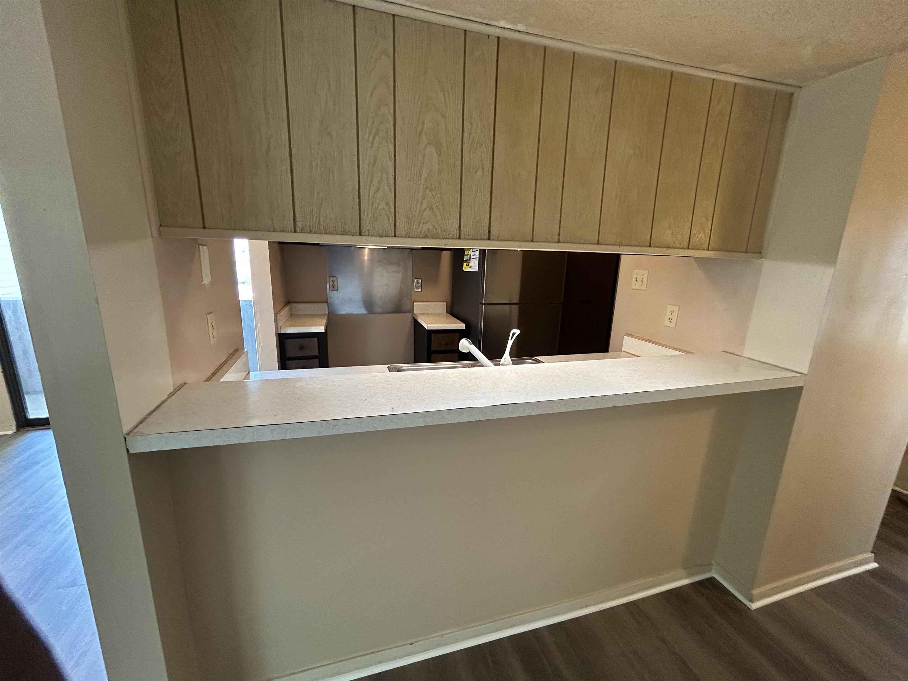 2800 Clarke Road, Unit 2 Memphis, TN 38115 - Photo 7 of 18 Kitchen pass-through with wood-finish upper cabinetry, a light-colored countertop, and a double-basin sink with a white faucet