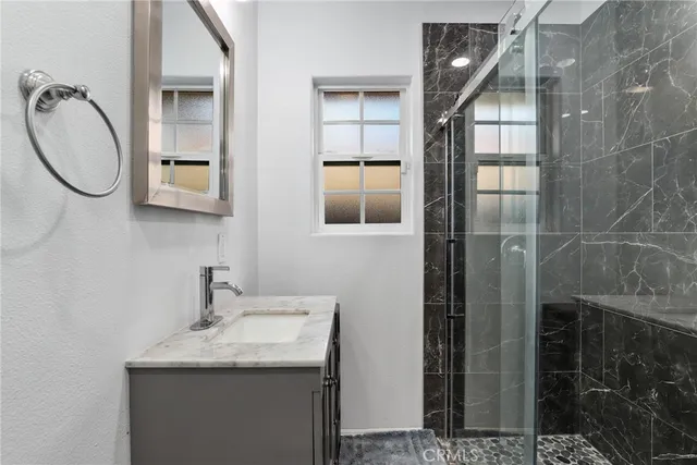 a bathroom with a granite countertop shower a mirror and a sink