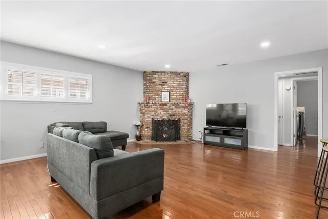 a living room with furniture a fireplace a flat screen tv and wooden floor