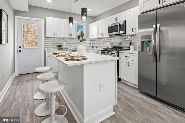 a kitchen with stainless steel appliances a sink a stove a refrigerator cabinets and a dining table