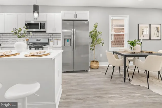 a kitchen with stainless steel appliances kitchen island granite countertop a refrigerator a stove a sink and chairs