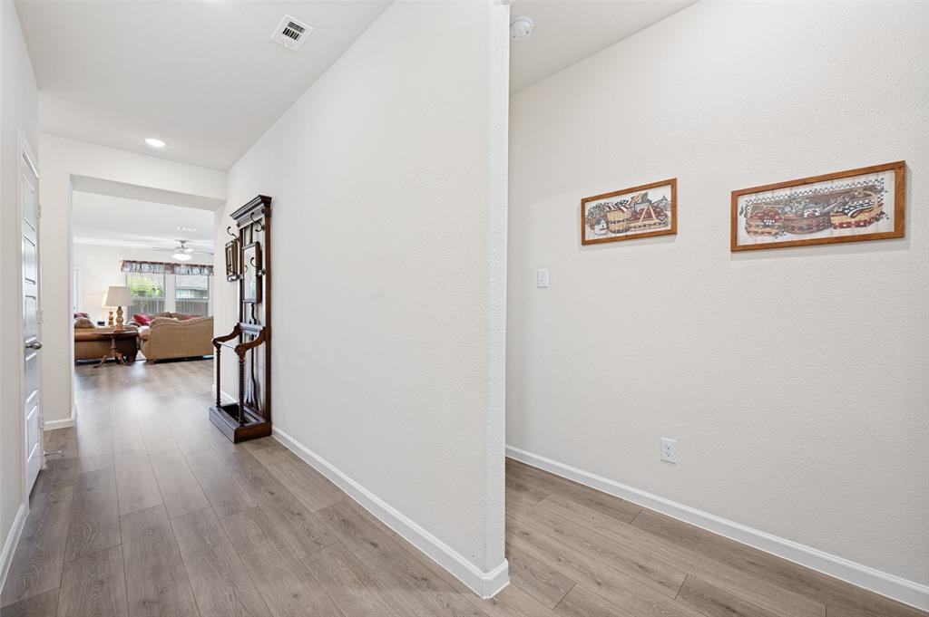 413 Wiggins Way Van Alstyne, TX 75495 - Photo 2 of 25 Hallway featuring wood-finish flooring, white baseboards, and neutral wall tones