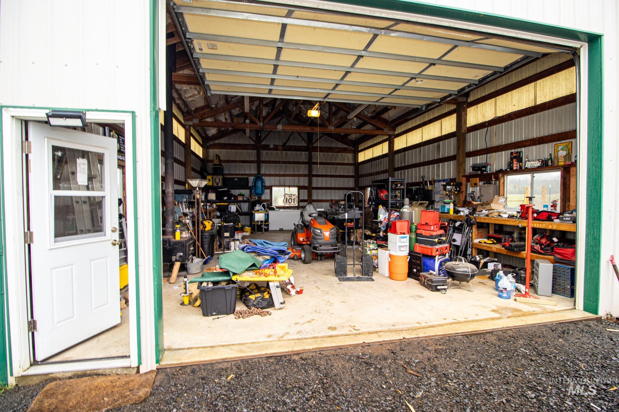 5404 Freeman Creek Road Lenore, ID 83541 - Photo 47 of 50 Spacious utility building featuring a large overhead door, a separate pedestrian entrance, exposed wood beam construction, corrugated wall paneling, and a concrete floor