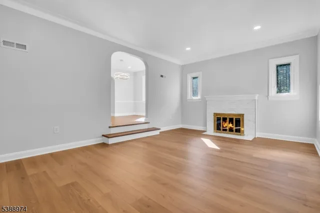 a view of an empty room with wooden floor a fireplace