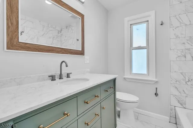 a bathroom with a granite countertop sink mirror and toilet