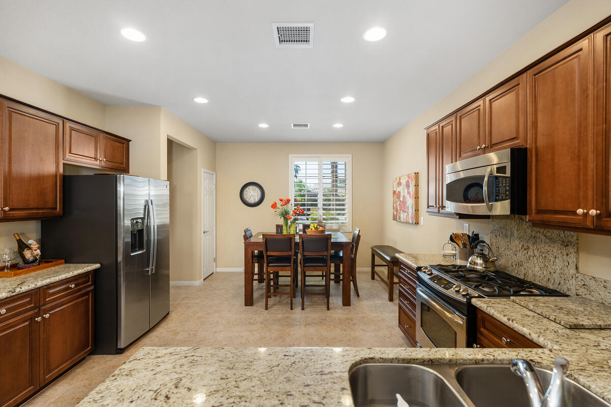 81220 Corte Tolon Indio, CA 92203 - Photo 10 of 42 a kitchen with stainless steel appliances granite countertop a stove top oven a sink dishwasher a dining table and chairs with wooden floor