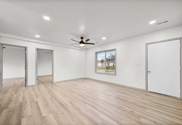 a view of an empty room with wooden floor and a window