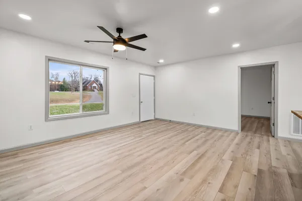 a view of empty room with wooden floor and fan
