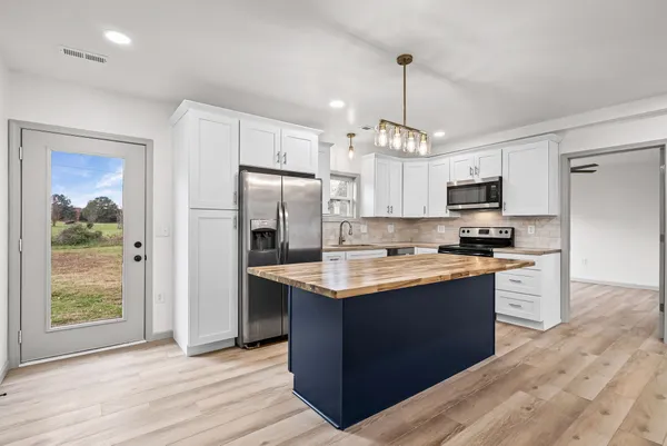 a kitchen with stainless steel appliances granite countertop a refrigerator a stove a sink and a microwave