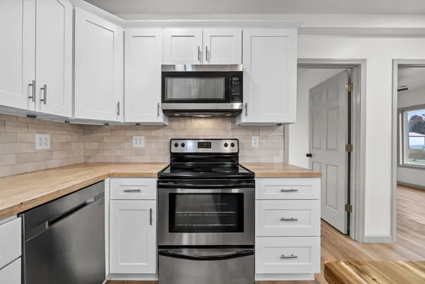 a kitchen with stainless steel appliances granite countertop white cabinets and a stove a oven with white countertops