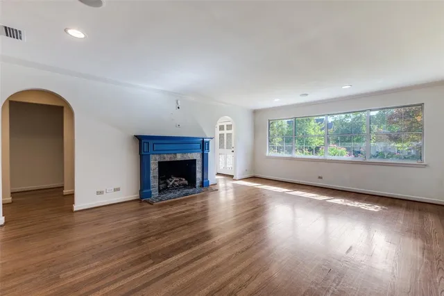an empty room with wooden floor fireplace and windows