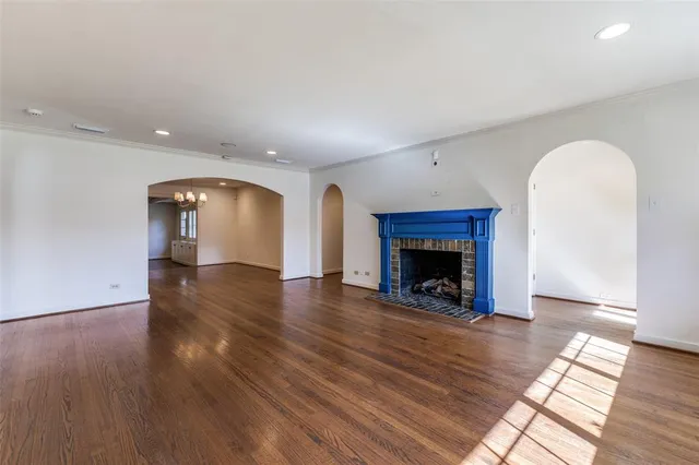 a view of an empty room with wooden floor fireplace and a window