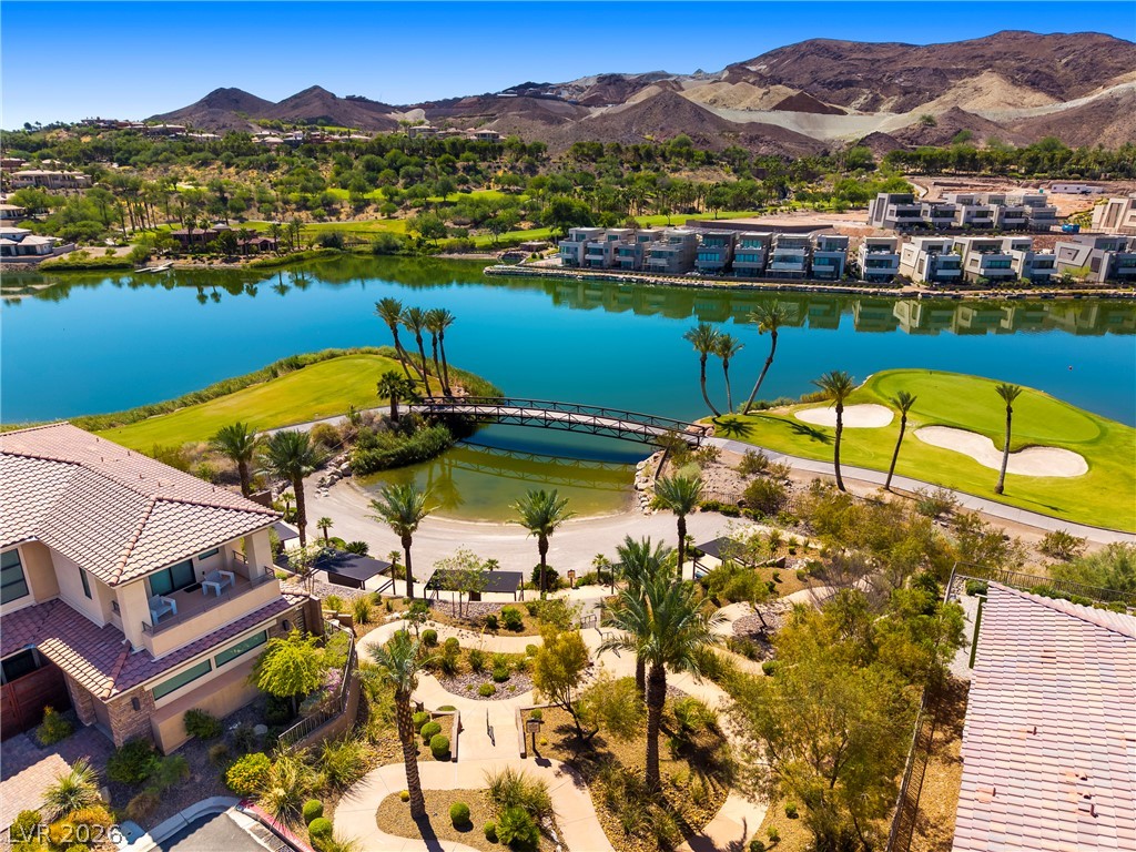 45 Garibaldi Way Henderson, NV 89011 - Photo 53 of 74 An aerial perspective reveals a vibrant golf course island nestled within a glistening lake, surrounded by desert mountains.