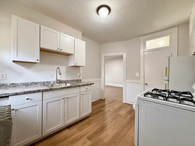 a kitchen with granite countertop a sink stove and cabinets
