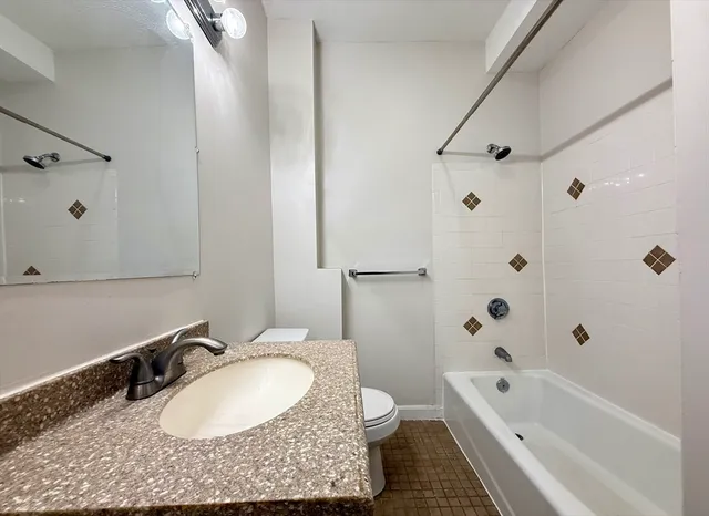 a bathroom with a granite countertop sink a toilet and shower