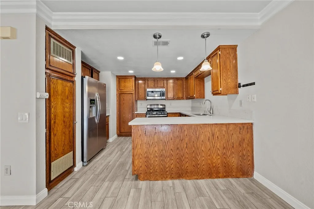 25118 Steinbeck Avenue Stevenson Ranch, CA 91381 - Photo 12 of 34 a large kitchen with stainless steel appliances granite countertop a refrigerator a sink dishwasher a stove and white countertops with wooden floor