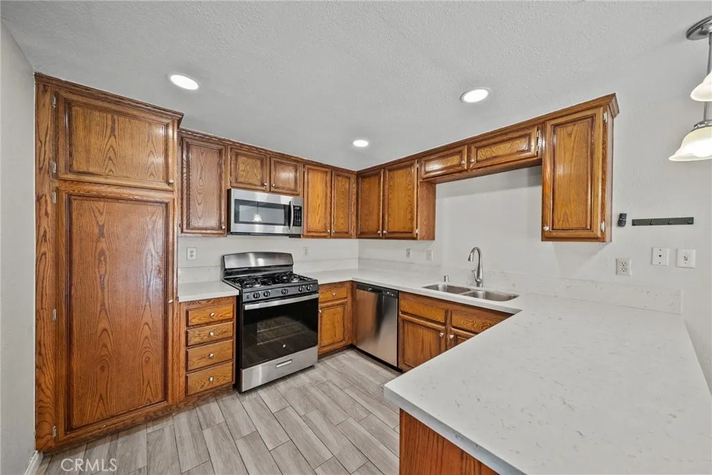 25118 Steinbeck Avenue Stevenson Ranch, CA 91381 - Photo 13 of 34 a kitchen with granite countertop stainless steel appliances and wooden cabinets