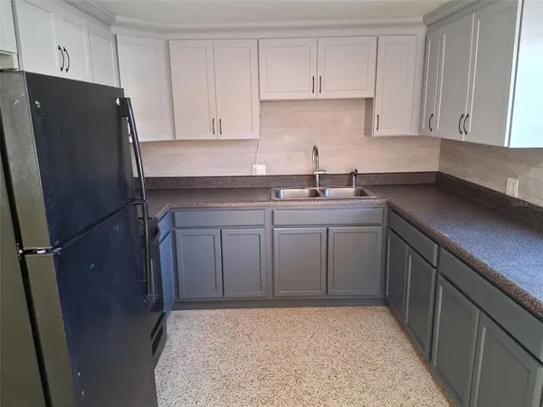 a kitchen with a sink a refrigerator and cabinets