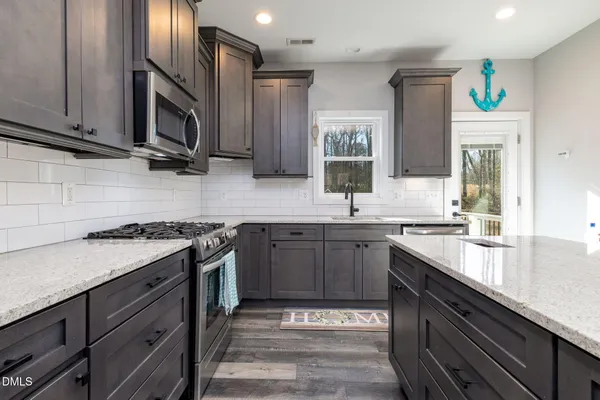 a kitchen with stainless steel appliances granite countertop a sink stove and microwave