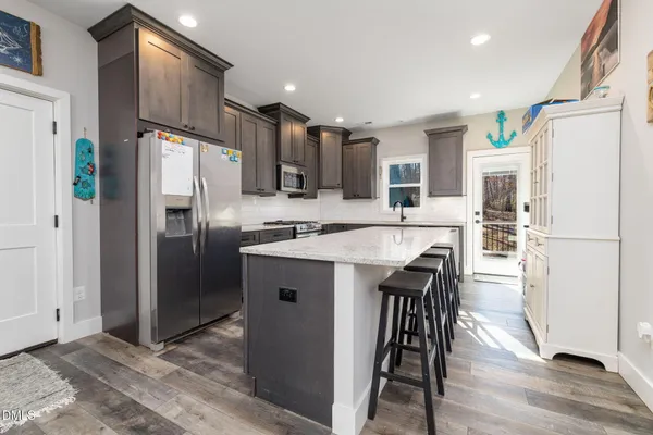 a kitchen with stainless steel appliances granite countertop a refrigerator a stove a sink a dining table and chairs